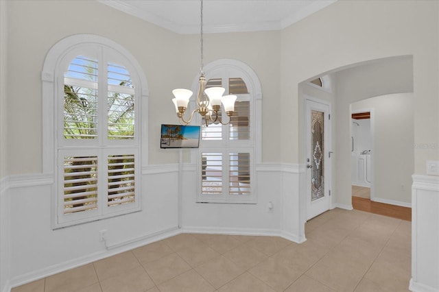 foyer featuring ornamental molding, arched walkways, and light tile patterned flooring