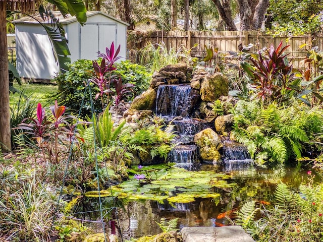 view of yard featuring a storage shed and a garden pond