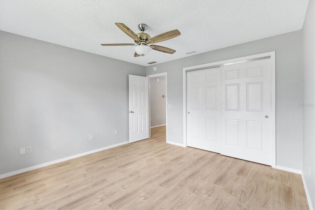 unfurnished bedroom featuring a closet, ceiling fan, light hardwood / wood-style floors, and a textured ceiling