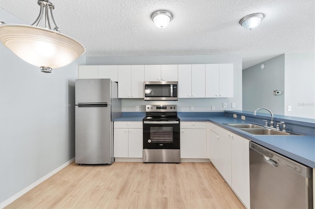 kitchen with appliances with stainless steel finishes, white cabinetry, sink, and pendant lighting