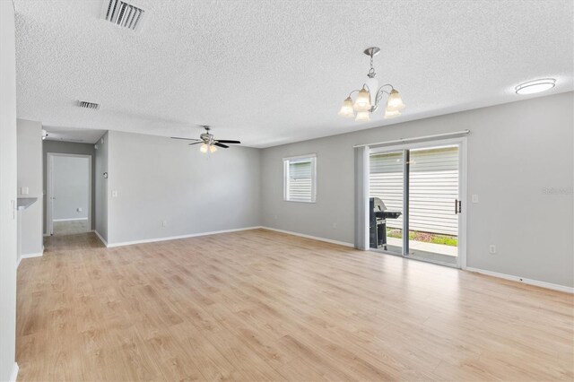 spare room with light wood-type flooring, ceiling fan with notable chandelier, and a textured ceiling