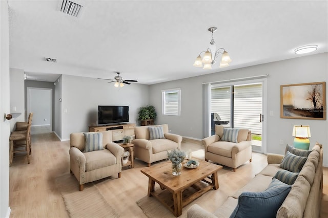 living room with ceiling fan with notable chandelier and light hardwood / wood-style flooring