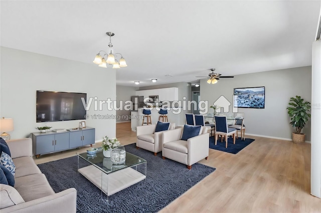 living room featuring light hardwood / wood-style flooring and ceiling fan with notable chandelier