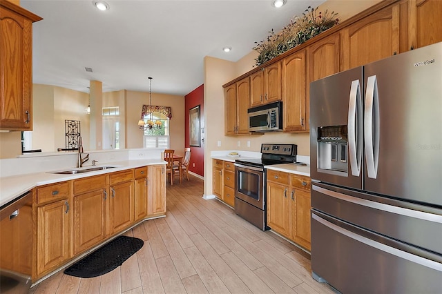 kitchen with sink, decorative light fixtures, appliances with stainless steel finishes, an inviting chandelier, and light wood-type flooring