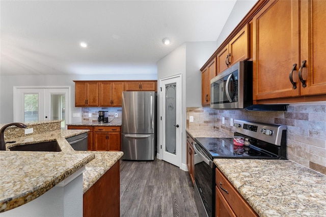 kitchen featuring stainless steel appliances, light stone counters, sink, decorative backsplash, and dark hardwood / wood-style floors