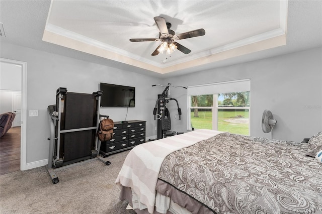 carpeted bedroom with ceiling fan, ornamental molding, and a tray ceiling