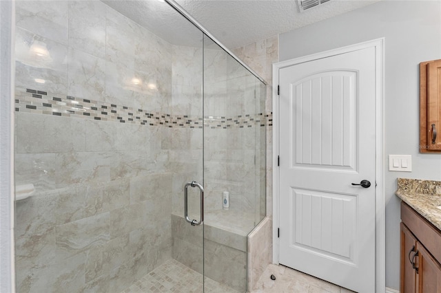 bathroom featuring a shower with shower door, a textured ceiling, and vanity