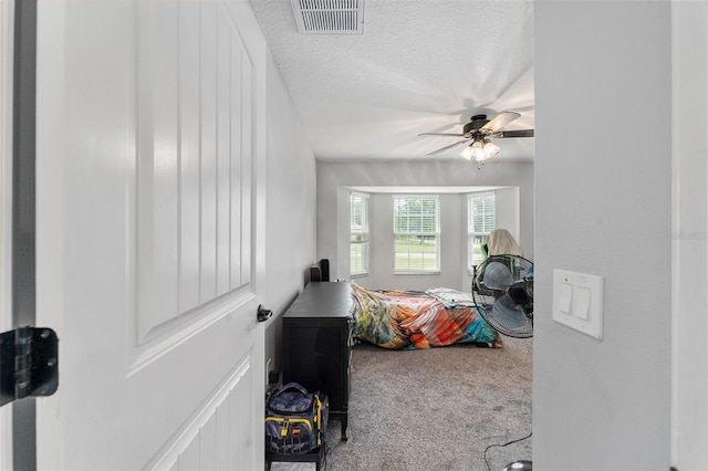 bedroom with a textured ceiling, ceiling fan, and carpet