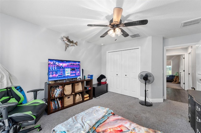 carpeted bedroom with a textured ceiling, ceiling fan, and a closet