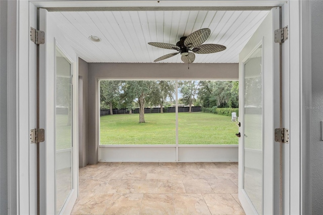 unfurnished sunroom featuring a healthy amount of sunlight and ceiling fan