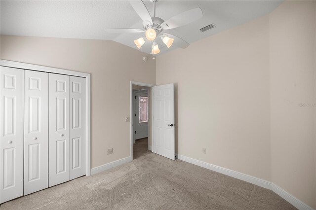 unfurnished bedroom featuring vaulted ceiling, light carpet, a closet, and ceiling fan