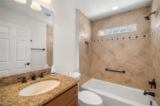 full bathroom with tiled shower / bath, vanity, a textured ceiling, and toilet