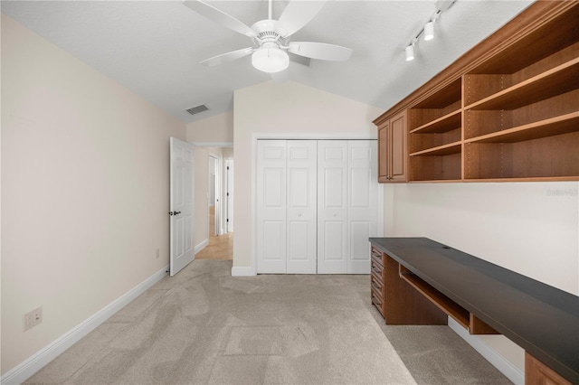 unfurnished office with rail lighting, ceiling fan, lofted ceiling, and light colored carpet