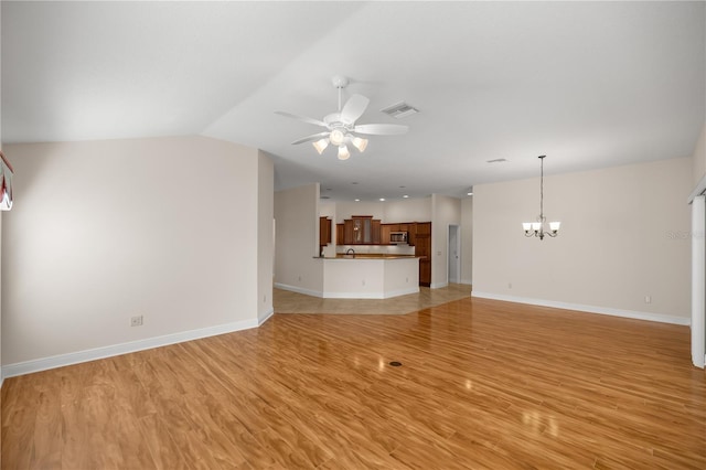 unfurnished living room with lofted ceiling, ceiling fan with notable chandelier, and light wood-type flooring