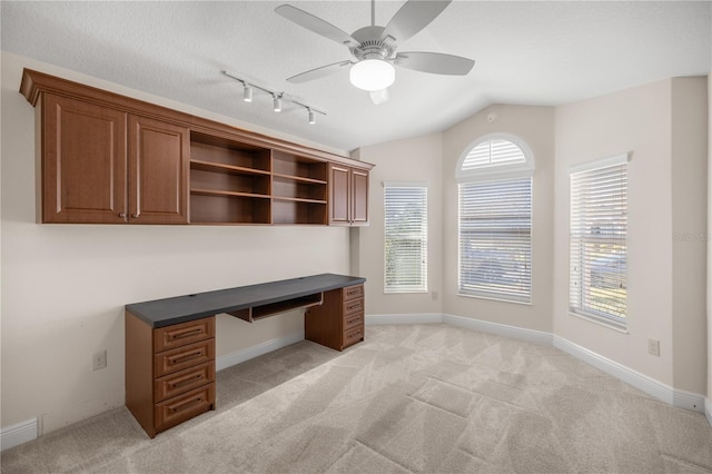 carpeted home office with built in desk, vaulted ceiling, rail lighting, a textured ceiling, and ceiling fan