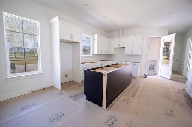 kitchen featuring a kitchen island, light wood-type flooring, and white cabinetry