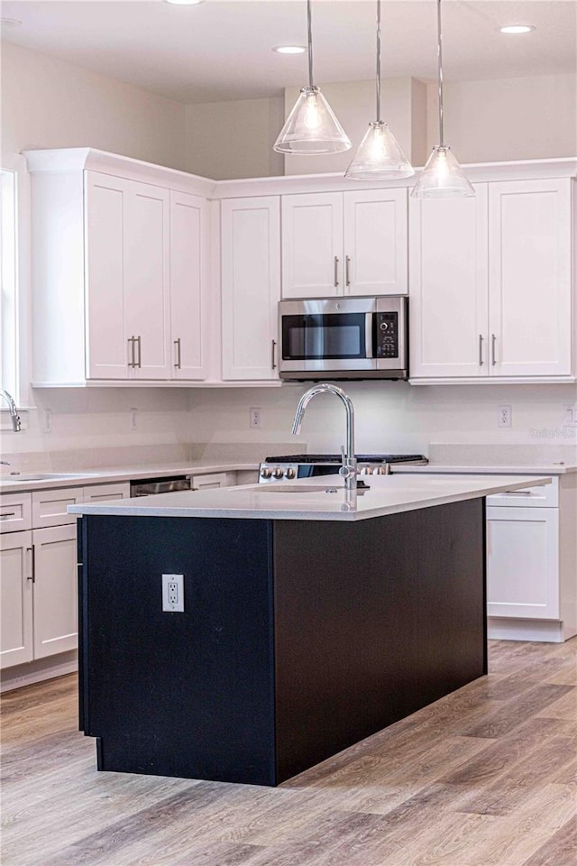 kitchen with white cabinetry, sink, pendant lighting, and light wood-type flooring