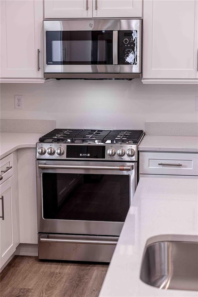 kitchen with white cabinets, appliances with stainless steel finishes, and light wood-type flooring