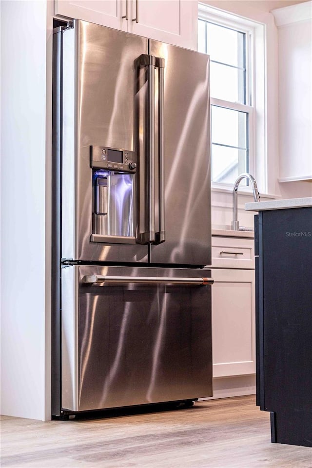 kitchen with high end refrigerator, light hardwood / wood-style floors, and white cabinetry