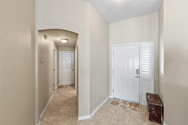 entrance foyer with baseboards, arched walkways, and a textured ceiling
