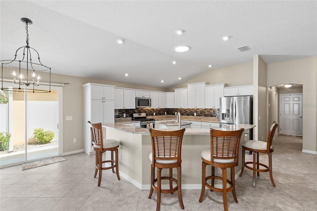 kitchen featuring tasteful backsplash, visible vents, arched walkways, stainless steel appliances, and lofted ceiling