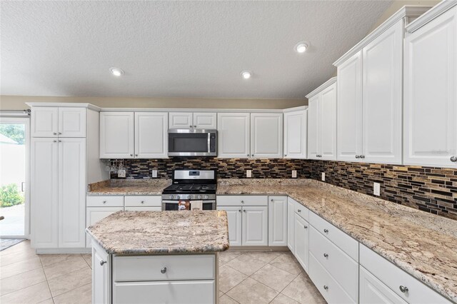 kitchen featuring light stone countertops, white cabinets, stainless steel appliances, and light tile patterned flooring