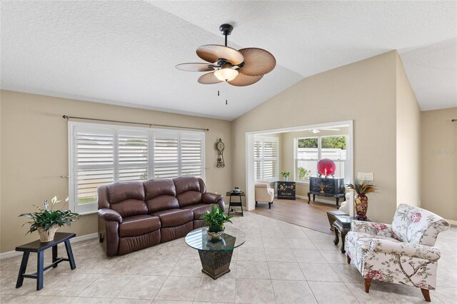 living room with lofted ceiling, light tile patterned floors, and ceiling fan