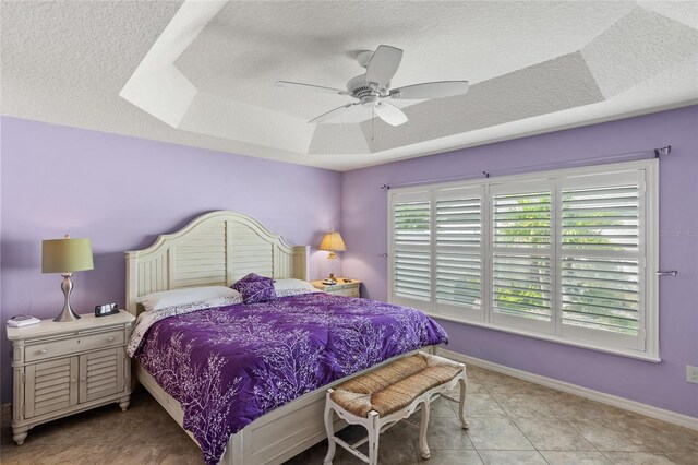 tiled bedroom with a raised ceiling and ceiling fan