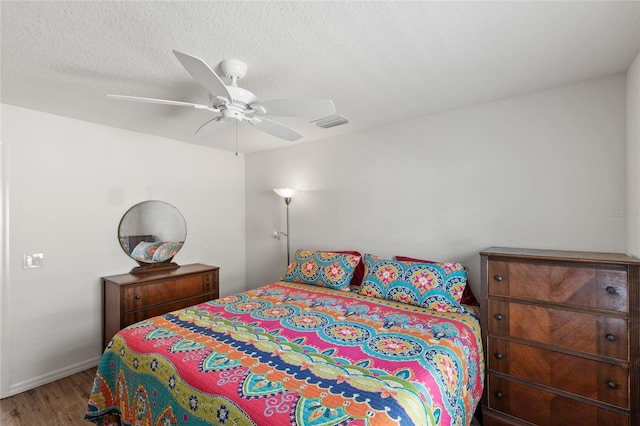 bedroom with visible vents, baseboards, a ceiling fan, and wood finished floors