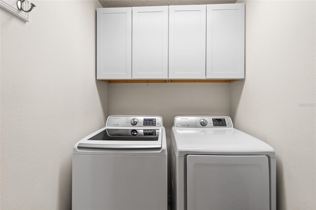 clothes washing area with cabinets and separate washer and dryer