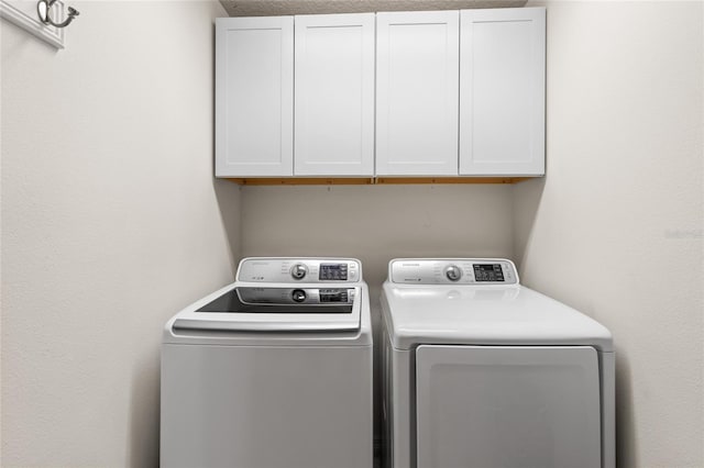clothes washing area featuring cabinet space and independent washer and dryer