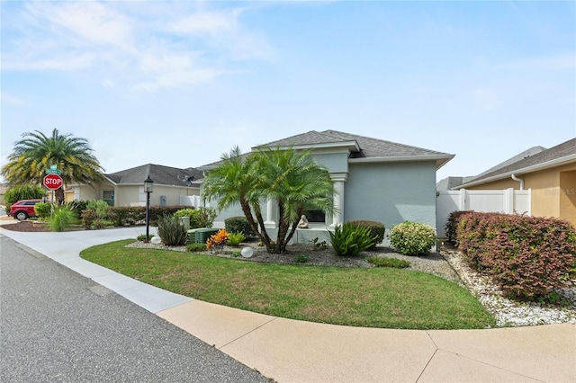 view of front of property with a shingled roof, stucco siding, and a front yard
