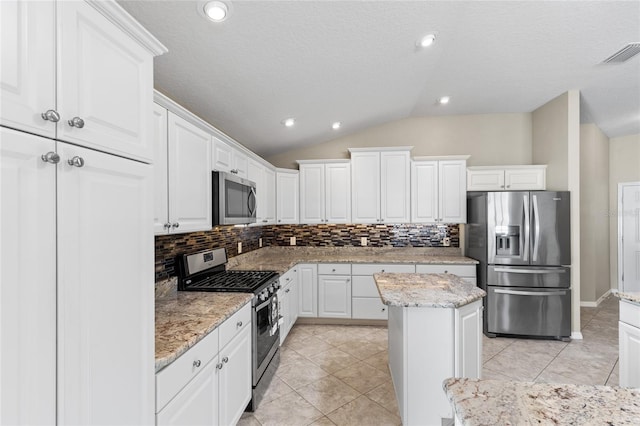 kitchen featuring lofted ceiling, backsplash, a center island, white cabinetry, and appliances with stainless steel finishes