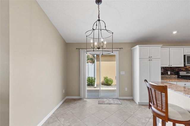 kitchen with backsplash, a notable chandelier, stove, hanging light fixtures, and white cabinets