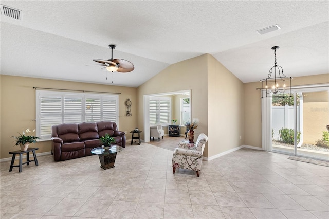 living room featuring vaulted ceiling, light tile patterned floors, a textured ceiling, and ceiling fan with notable chandelier