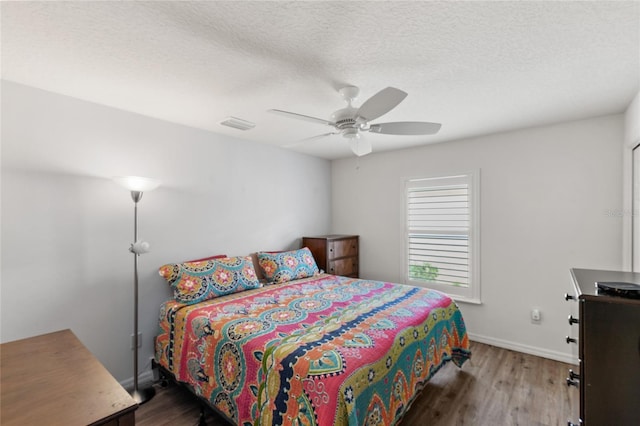 bedroom with a textured ceiling, ceiling fan, and dark hardwood / wood-style flooring