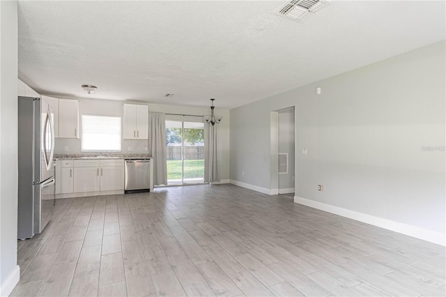 interior space with white cabinets, stainless steel appliances, sink, and light hardwood / wood-style flooring