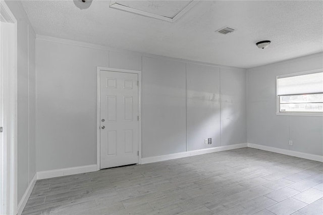 spare room featuring a textured ceiling and light hardwood / wood-style floors