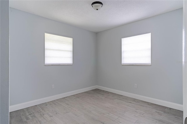 spare room featuring a textured ceiling and light hardwood / wood-style floors