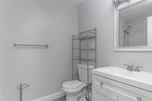 bathroom featuring a shower, toilet, and vanity