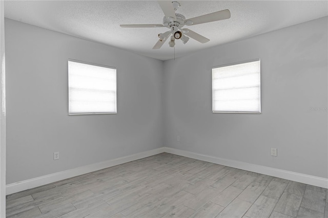 spare room with a textured ceiling, a healthy amount of sunlight, light hardwood / wood-style flooring, and ceiling fan