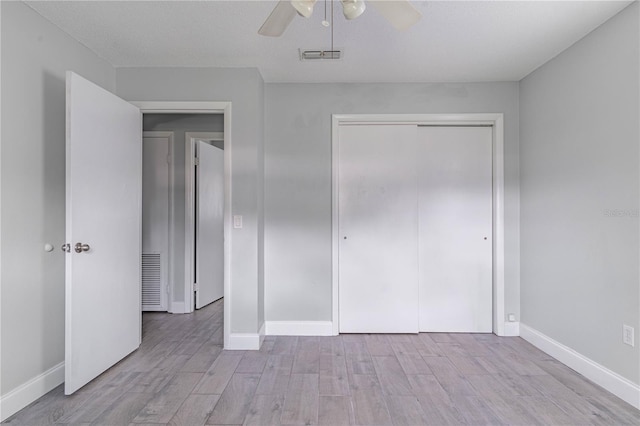 unfurnished bedroom featuring a closet, ceiling fan, light hardwood / wood-style floors, and a textured ceiling