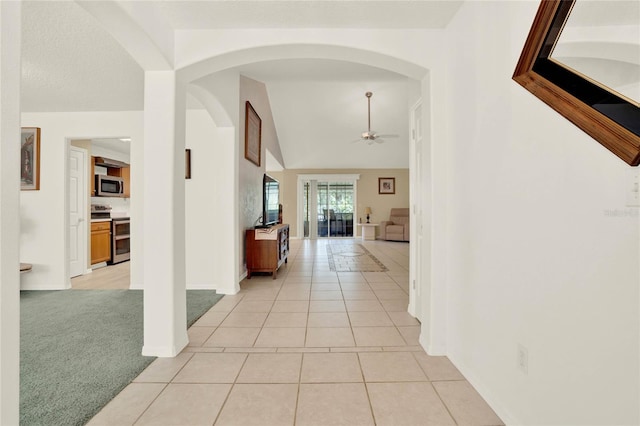 corridor with light tile patterned floors, baseboards, light carpet, and lofted ceiling