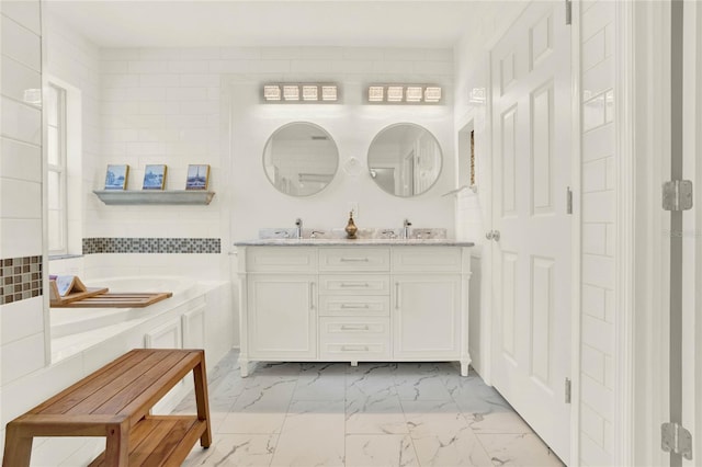 full bathroom with double vanity, a bath, marble finish floor, and a sink