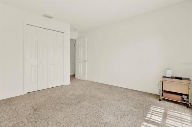 unfurnished bedroom featuring visible vents, a closet, and carpet flooring