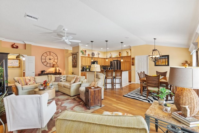 living room with lofted ceiling, ceiling fan with notable chandelier, crown molding, and light hardwood / wood-style flooring