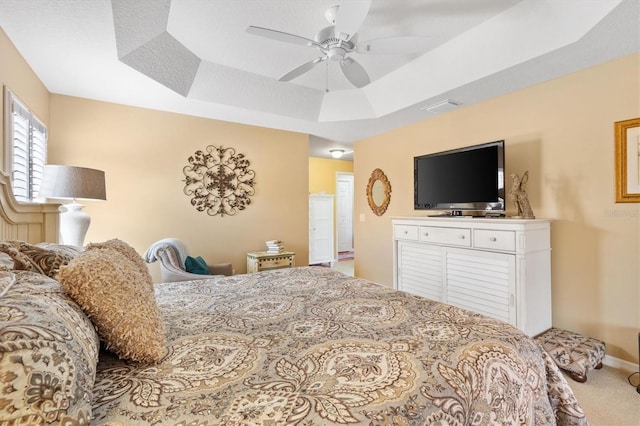 carpeted bedroom with a raised ceiling and ceiling fan