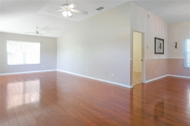 spare room featuring wood finished floors, visible vents, baseboards, ceiling fan, and vaulted ceiling