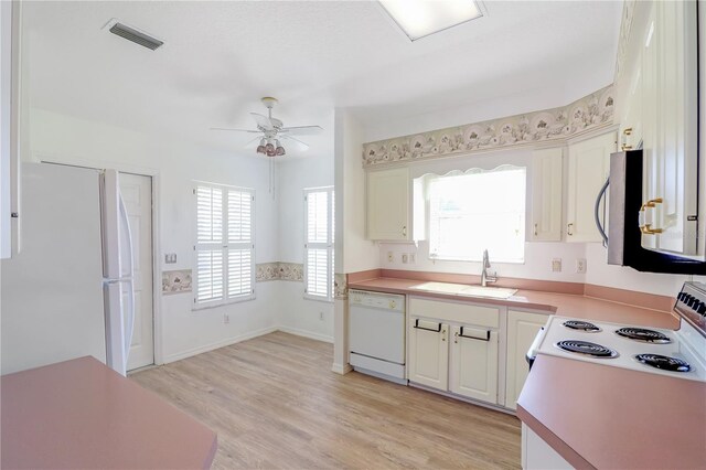 kitchen featuring white appliances, visible vents, light wood-style flooring, a sink, and light countertops