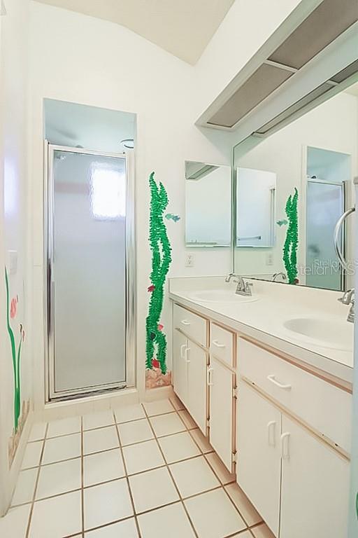 bathroom with walk in shower, vanity, and tile patterned flooring